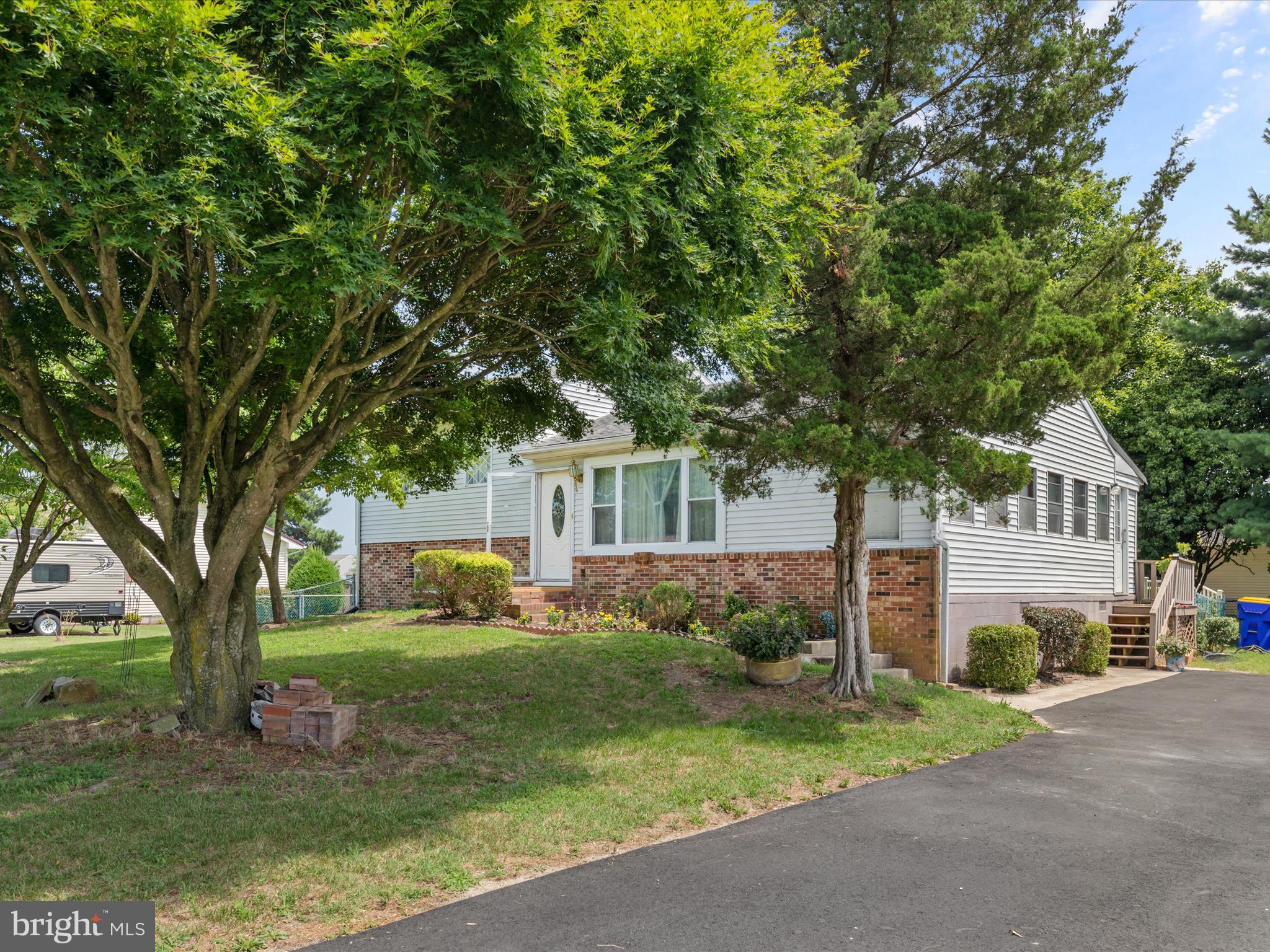 a front view of a house with garden and trees