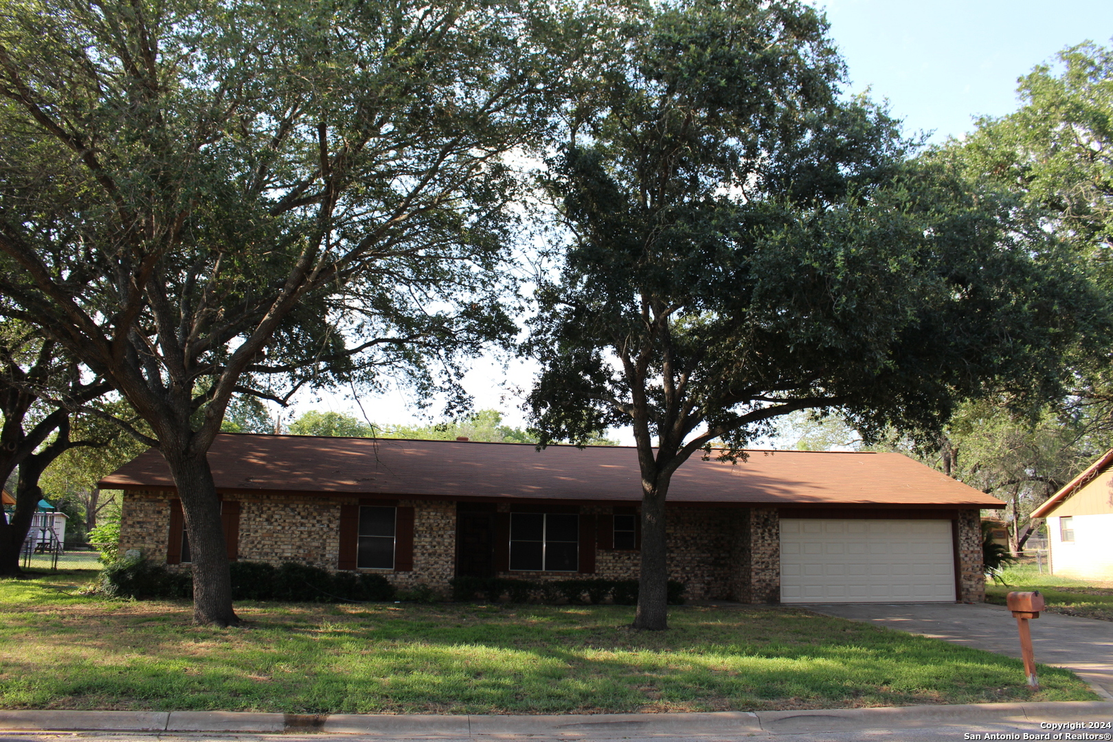 a front view of a house with a garden and tree