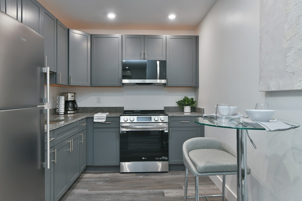 a kitchen with kitchen island granite countertop a sink stove and refrigerator