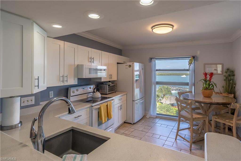 Kitchen featuring white cabinets, white appliances, a water view, and sink