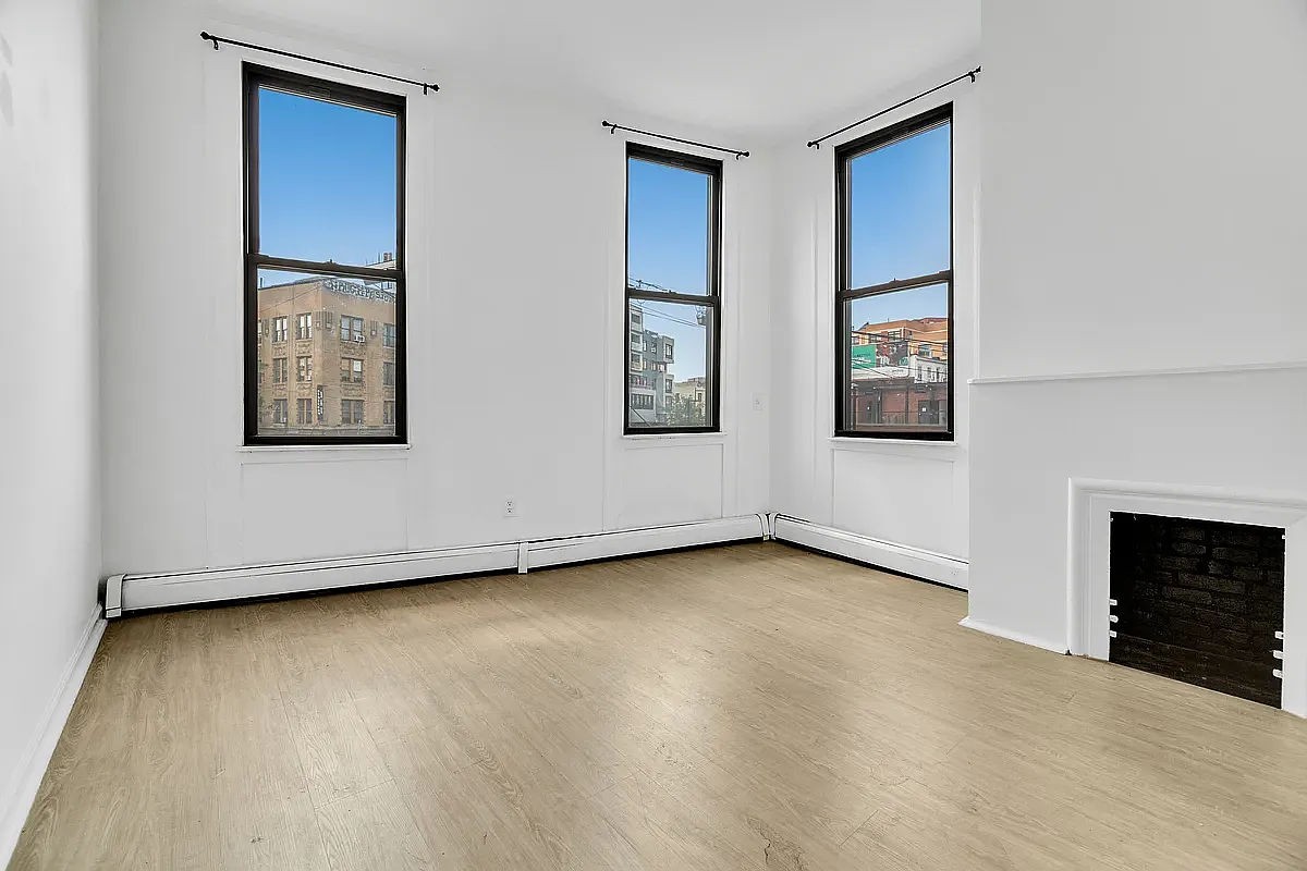 an empty room with windows and fireplace