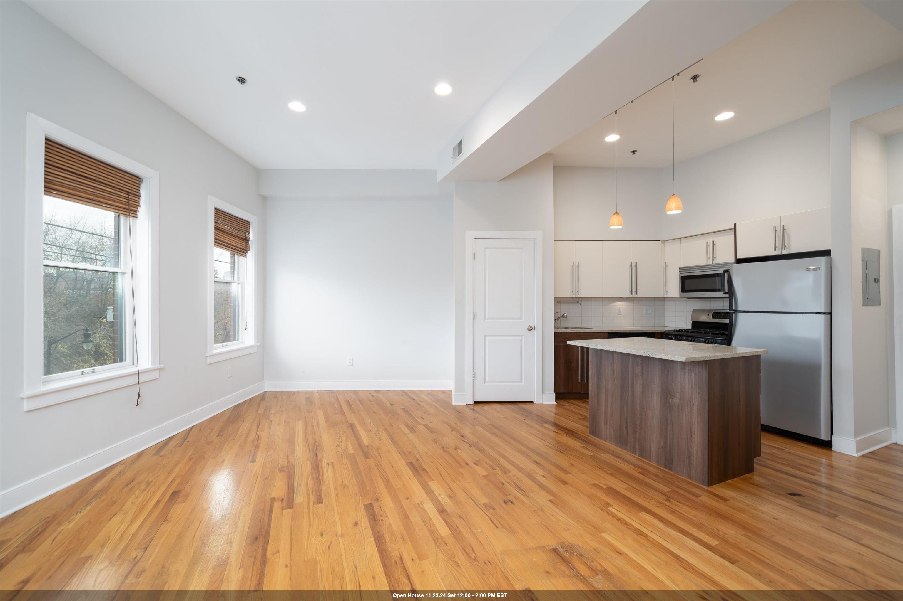 a large kitchen with kitchen island a large counter space wooden floor and stainless steel appliances