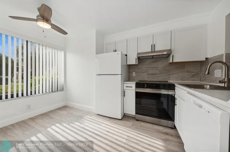 a kitchen with a refrigerator and white cabinets