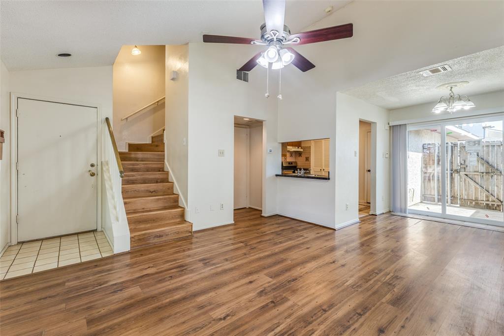 a view of an empty room with wooden floor and a ceiling fan