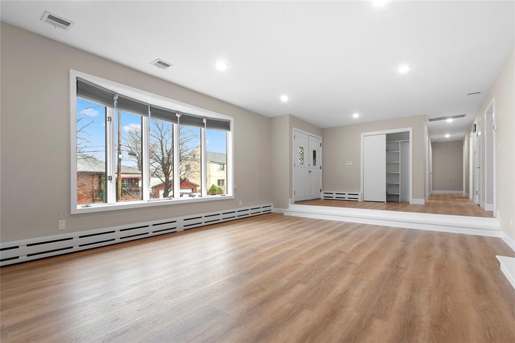 a view of an empty room with a window and wooden floor