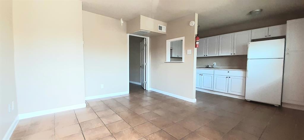 a view of a kitchen with a sink and dishwasher a refrigerator with white cabinets