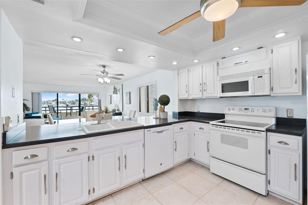 a kitchen with granite countertop white cabinets white appliances and a sink