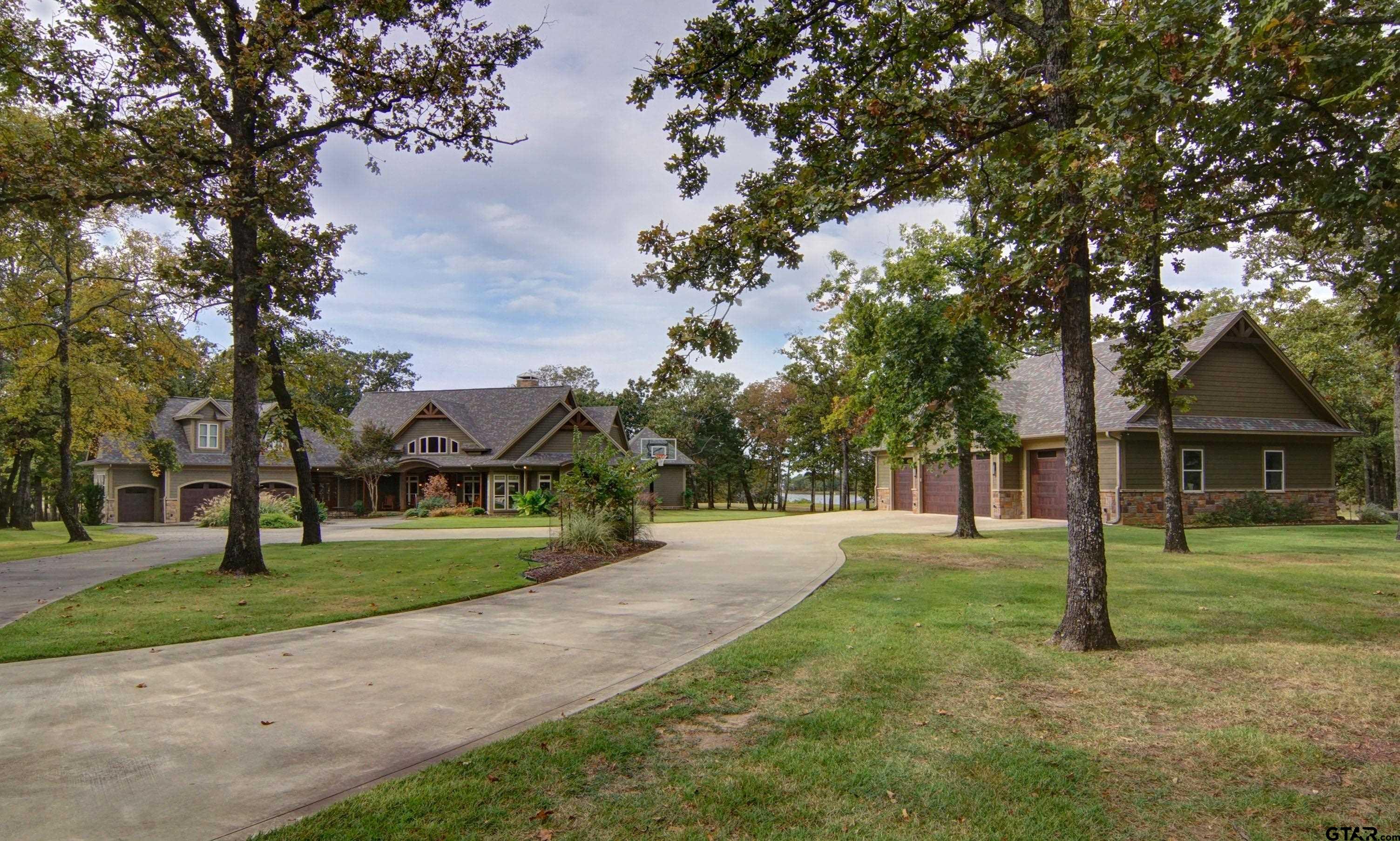 a view of a house with a big yard and large trees