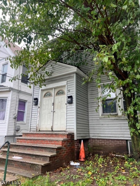 a front view of a house with a tree