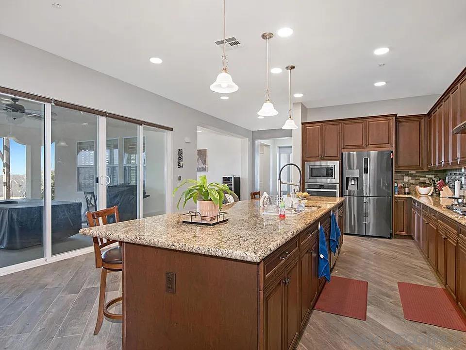 a kitchen with stainless steel appliances granite countertop a kitchen island a stove a table and chairs