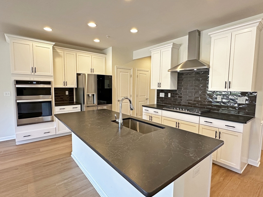 a large kitchen with stainless steel appliances a large counter top and a refrigerator