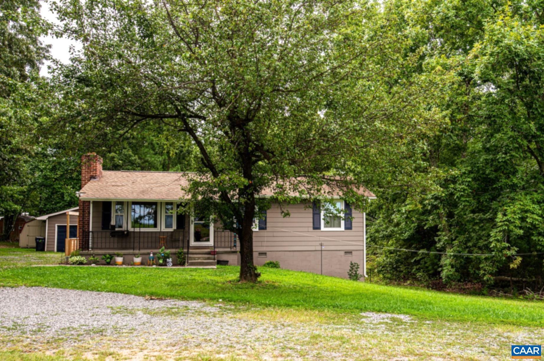 a view of a yard in front of a house with plants and large tree