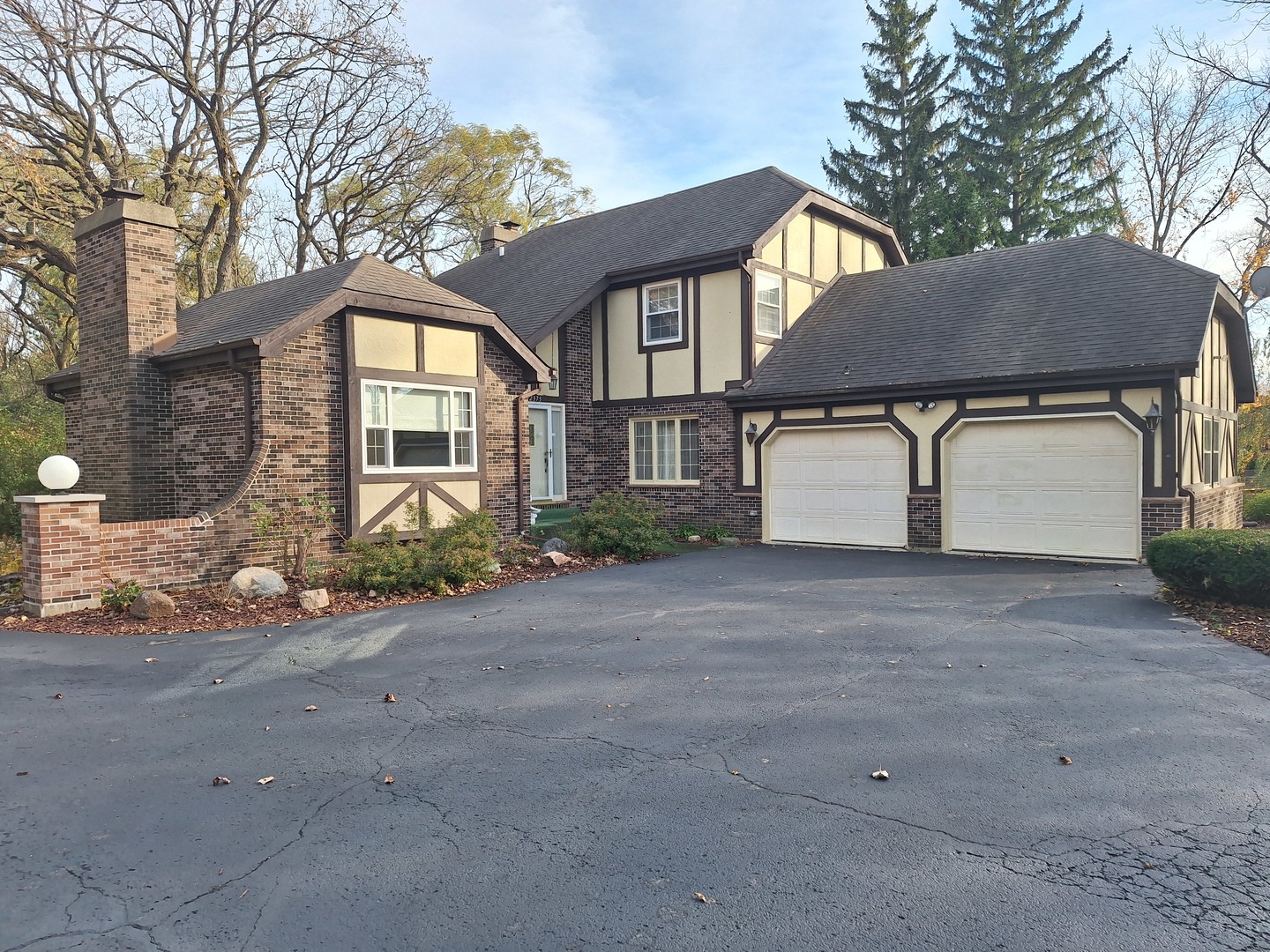 a front view of a house with a garden and trees