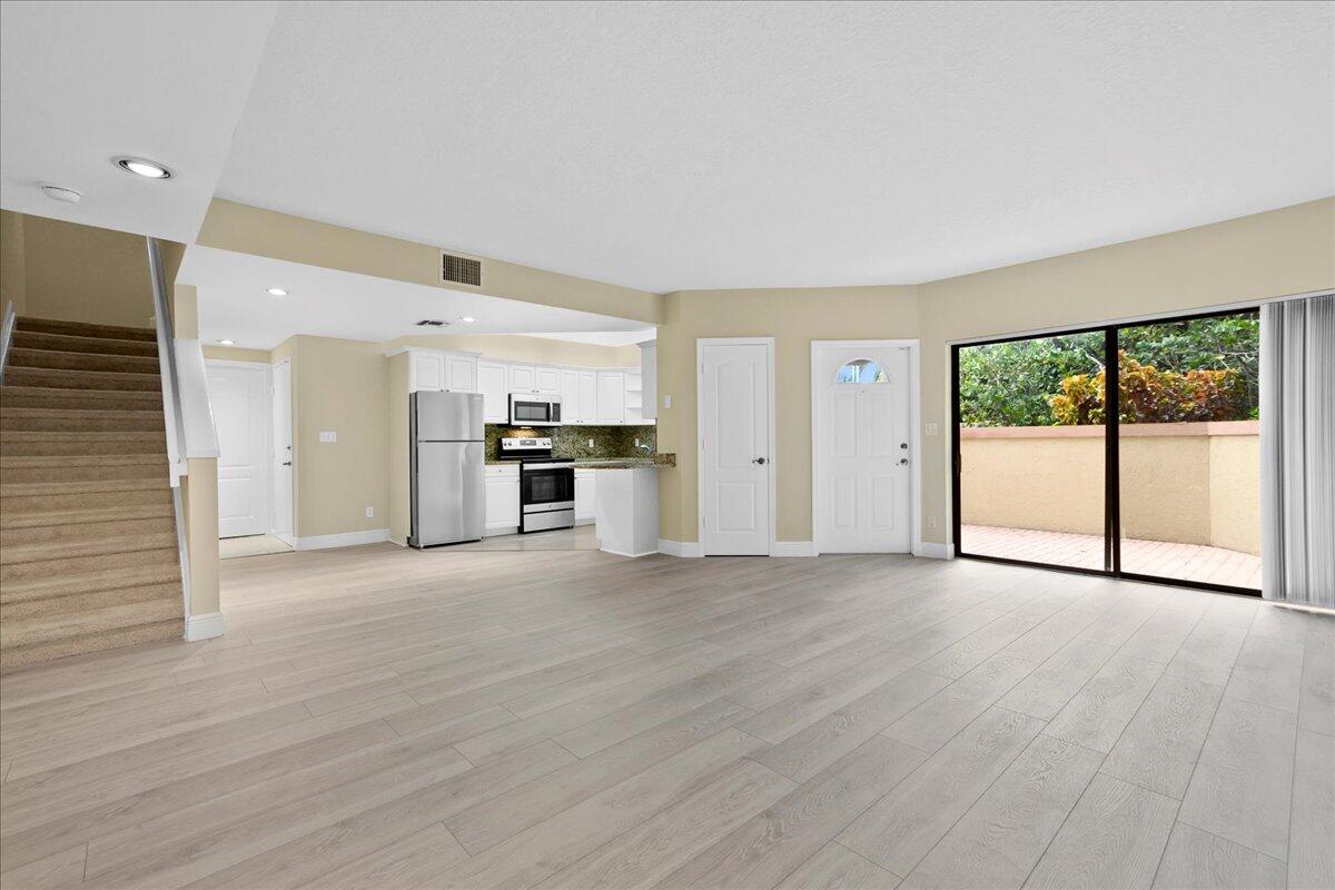 an empty room with wooden floor and a kitchen