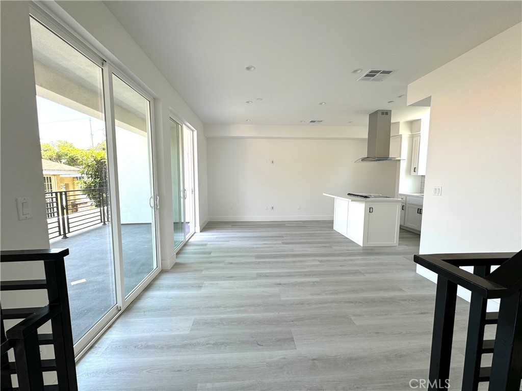 a view of kitchen and empty room with wooden floor