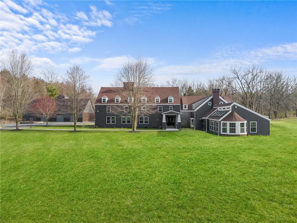 a view of a big house with a big yard and large trees