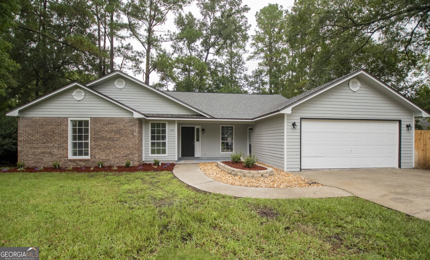 a front view of house with yard and trees all around