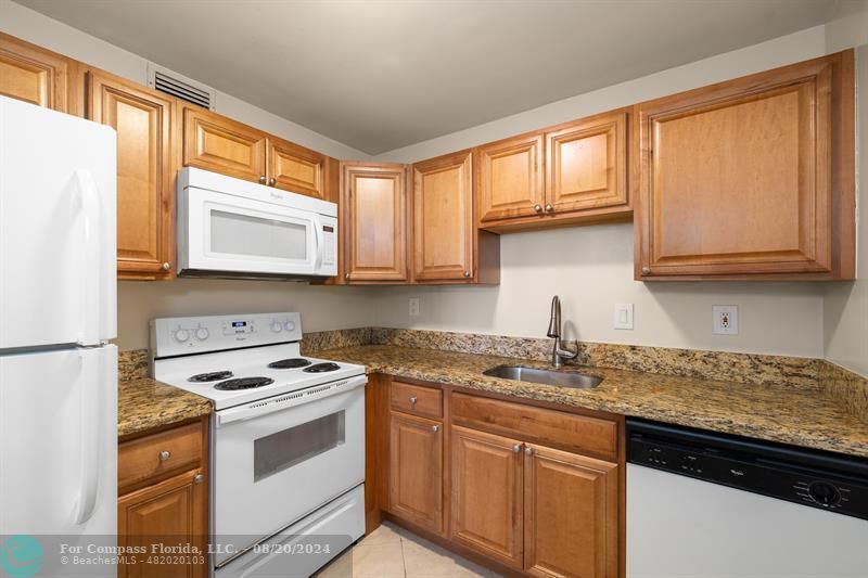 a kitchen with granite countertop cabinets stainless steel appliances a sink and a window