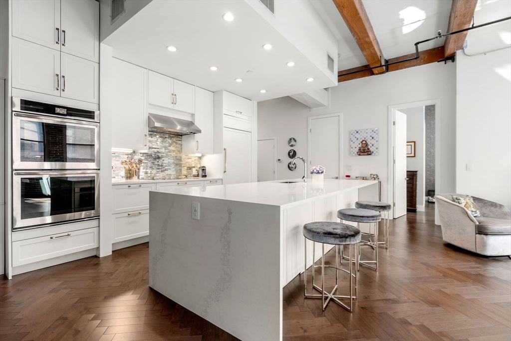 a kitchen with stainless steel appliances kitchen island granite countertop a table chairs stove and white cabinets