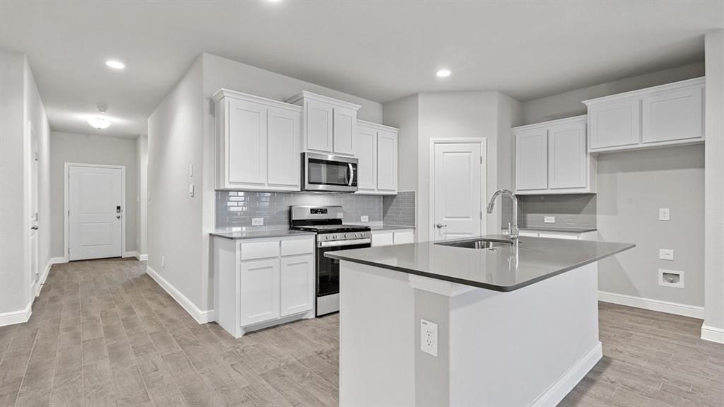 a kitchen with appliances a sink a counter top space cabinets and a window