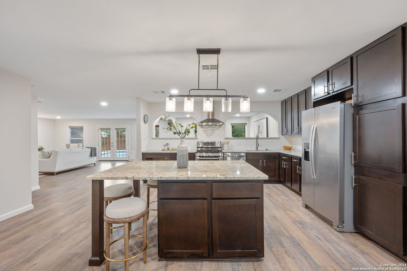 a kitchen with stainless steel appliances a dining table chairs and wooden floor