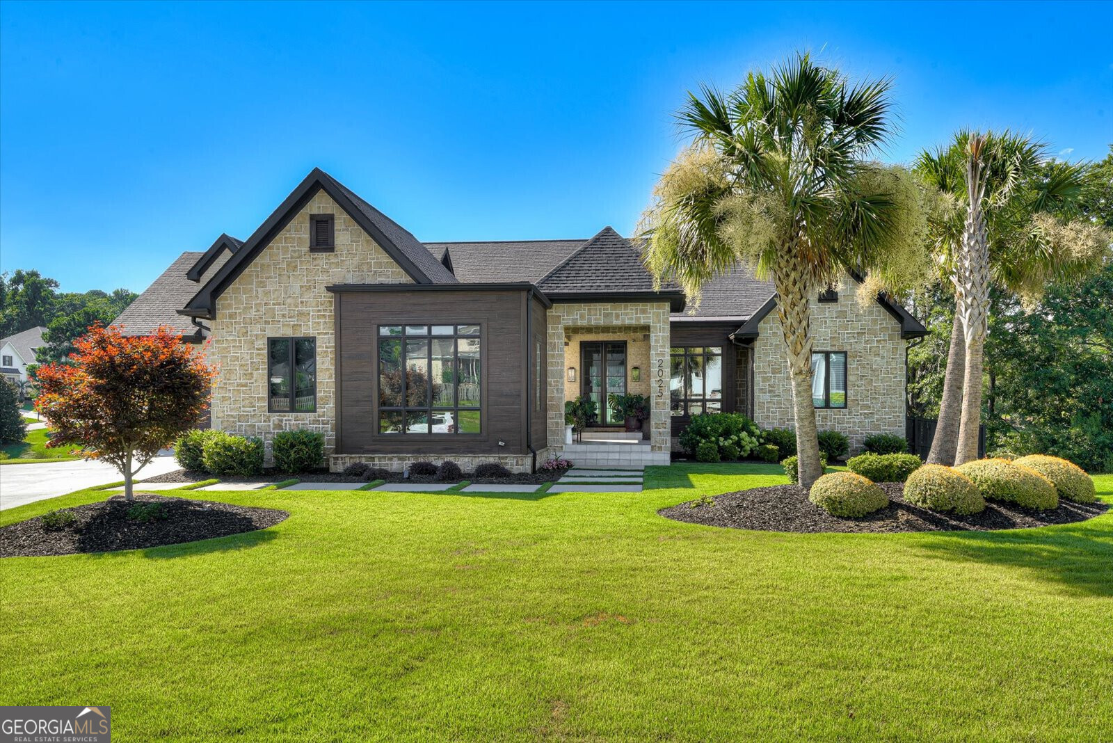 a front view of a house with garden and trees