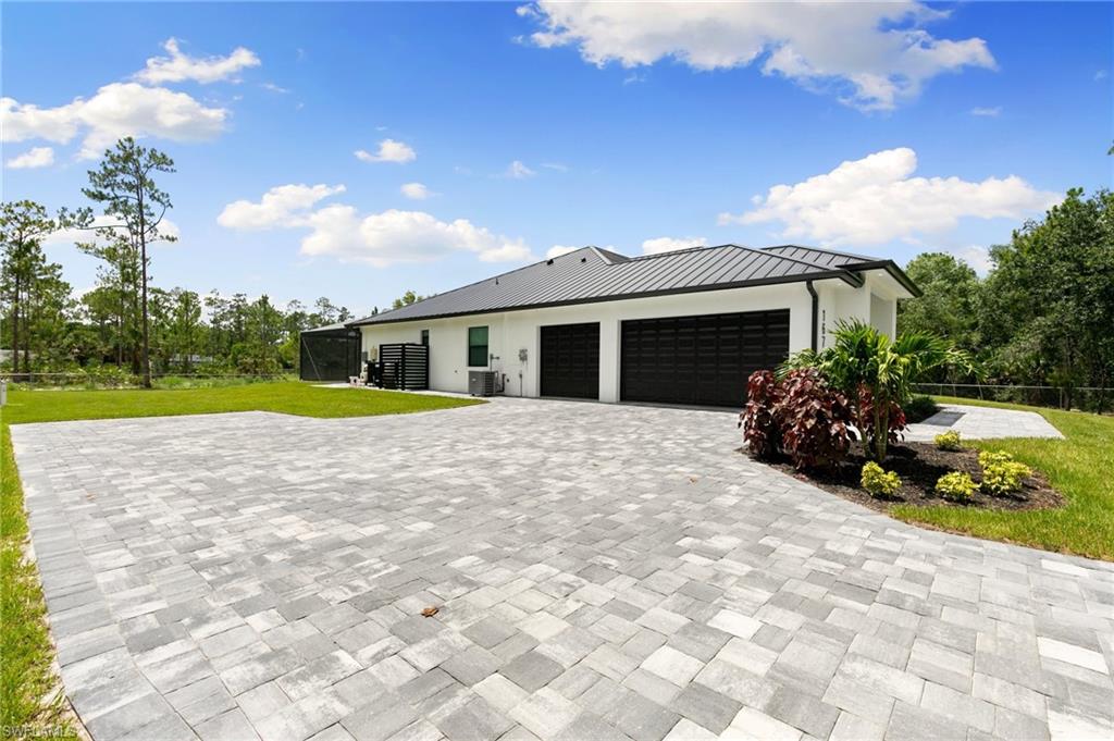 View of front of home featuring cooling unit, a front yard, and a garage