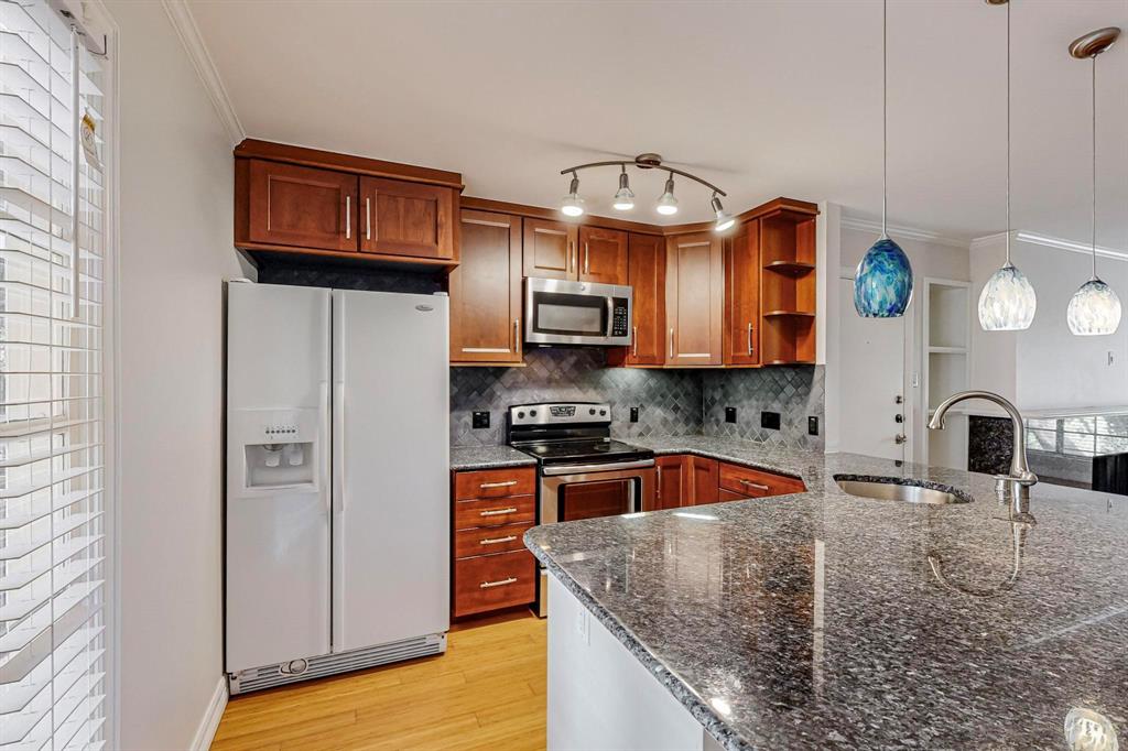 a kitchen with stainless steel appliances granite countertop a refrigerator a stove top oven a sink and dishwasher