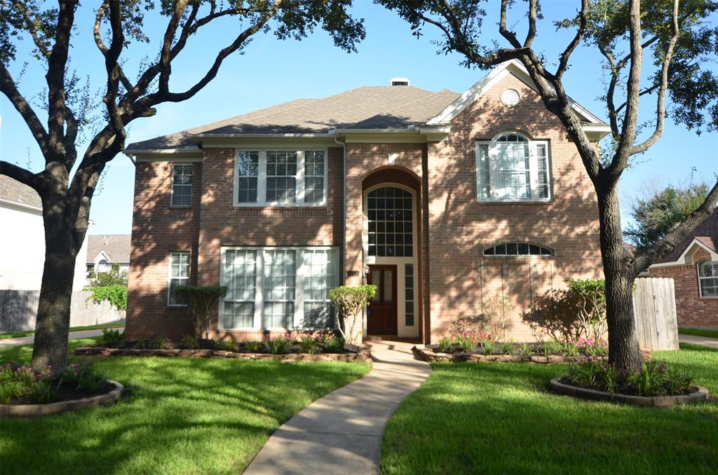 a front view of a house with a garden and tree