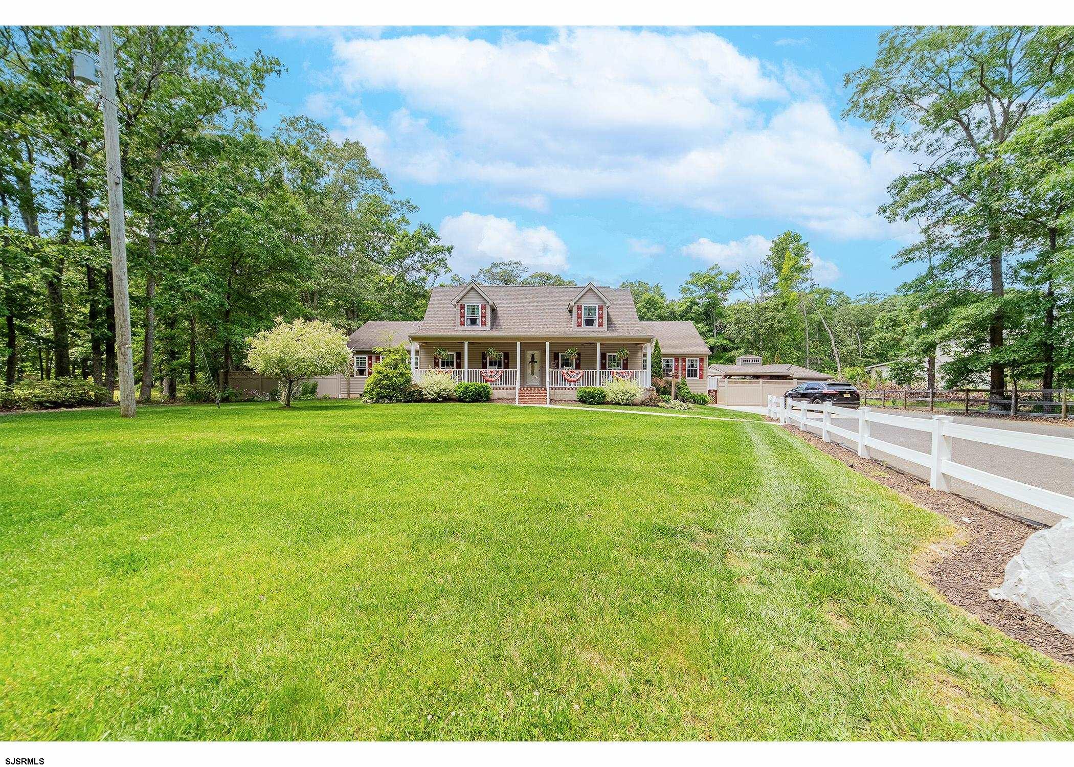 a view of a house with a big yard and large trees