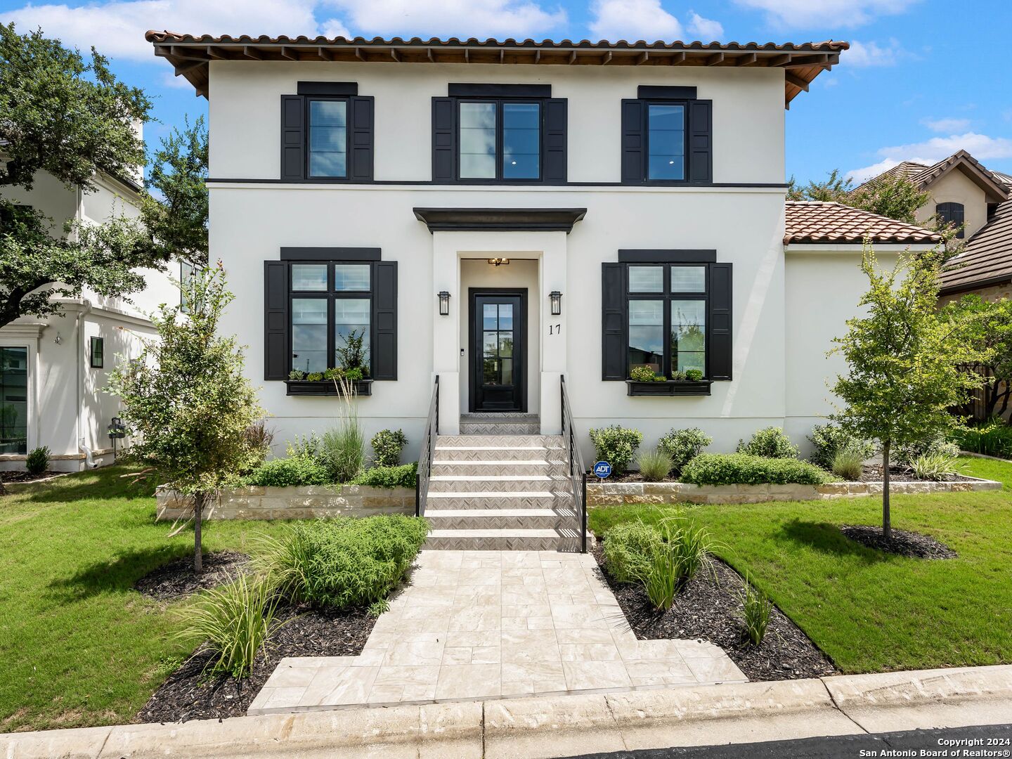 a front view of a house with a yard and potted plants