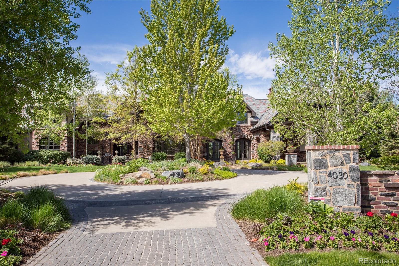 a front view of a house with garden and trees