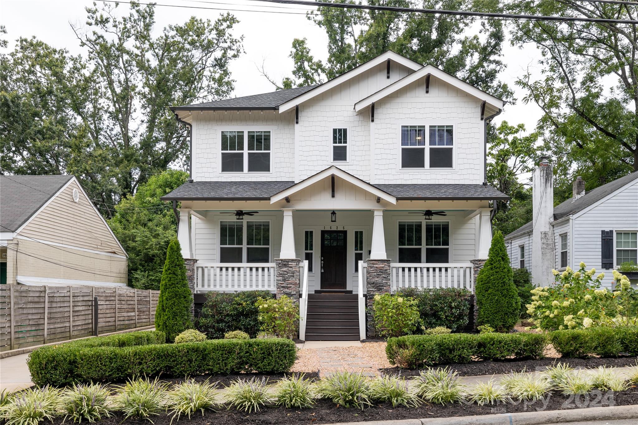 a front view of a house with a yard and potted plants