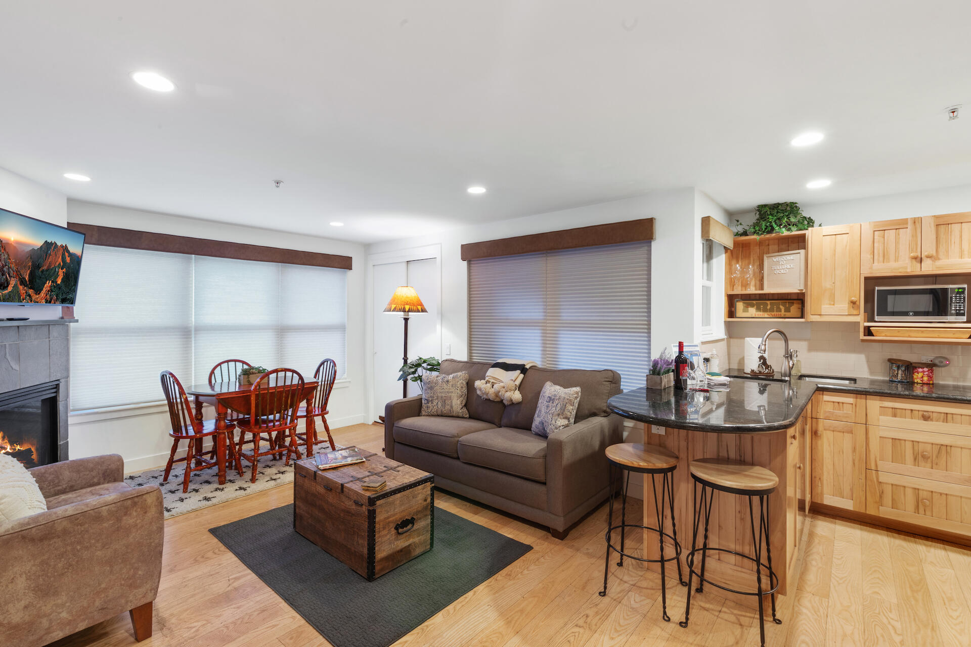 a living room with furniture kitchen view and a wooden floor