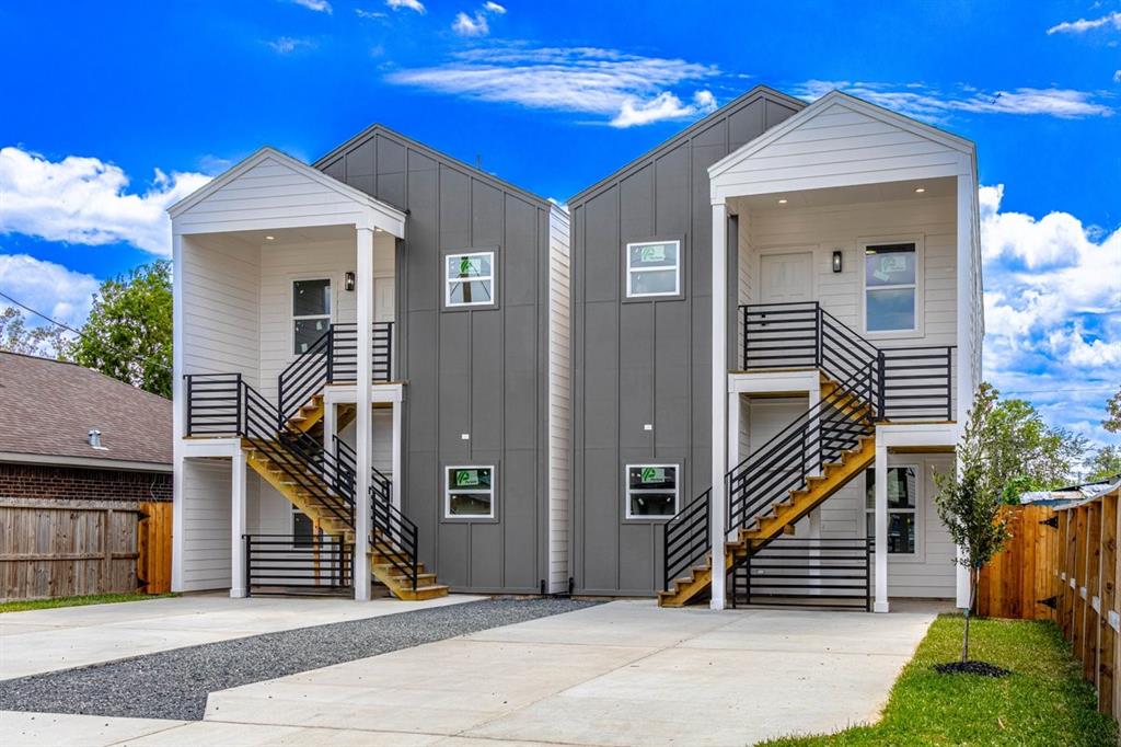 Modern duplex with a sleek gray exterior,  each unit has its own covered entryway, with ample parking space available out front.