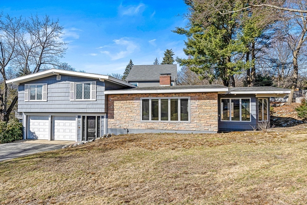 a front view of house with yard and trees in the background