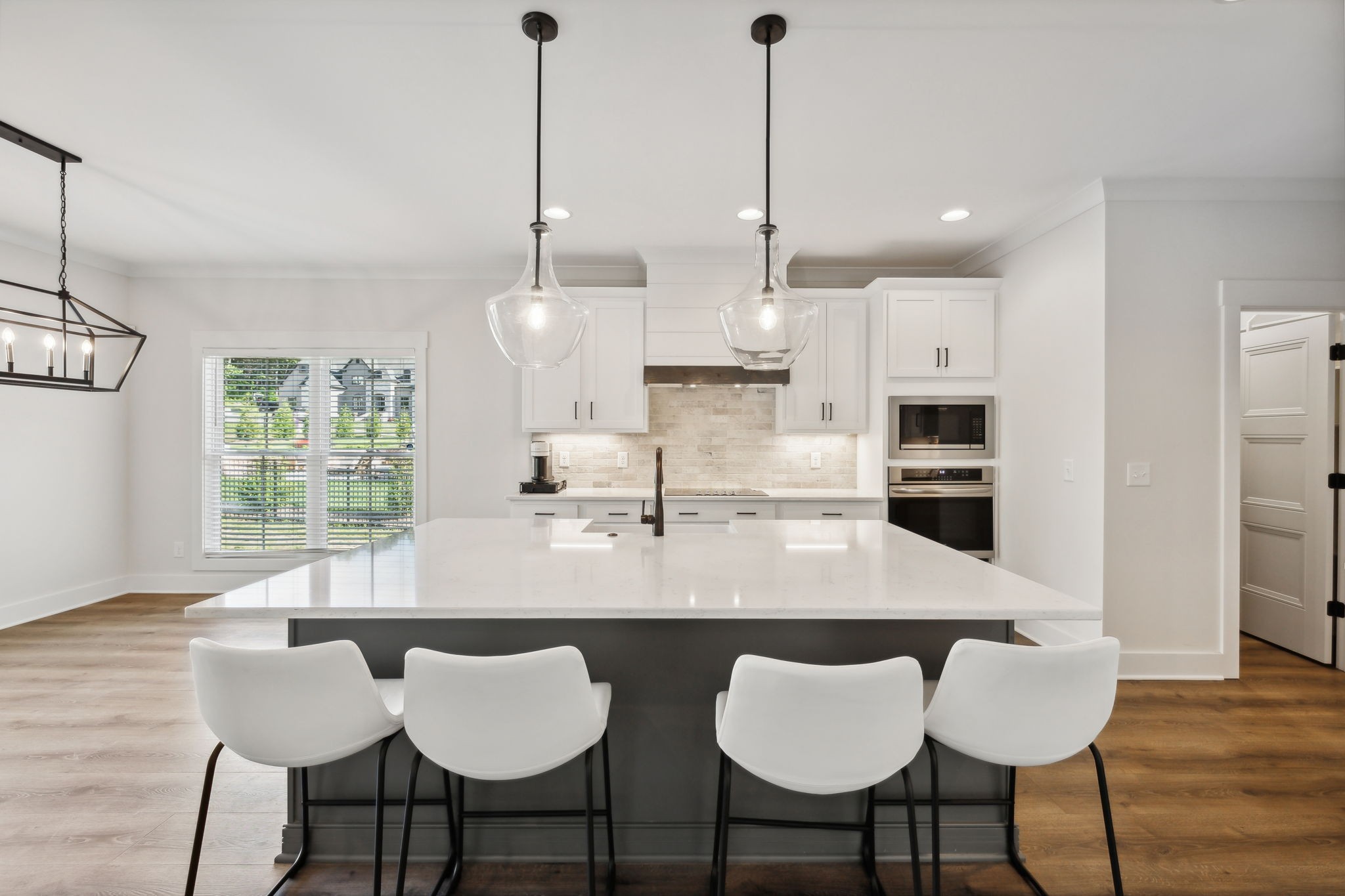 a kitchen with stainless steel appliances kitchen island granite countertop a dining table chairs and white cabinets