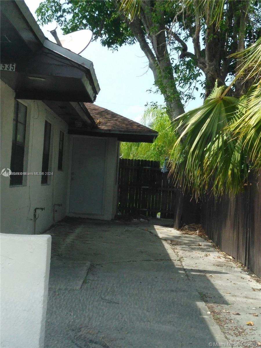 a backyard of a house with large trees and wooden fence