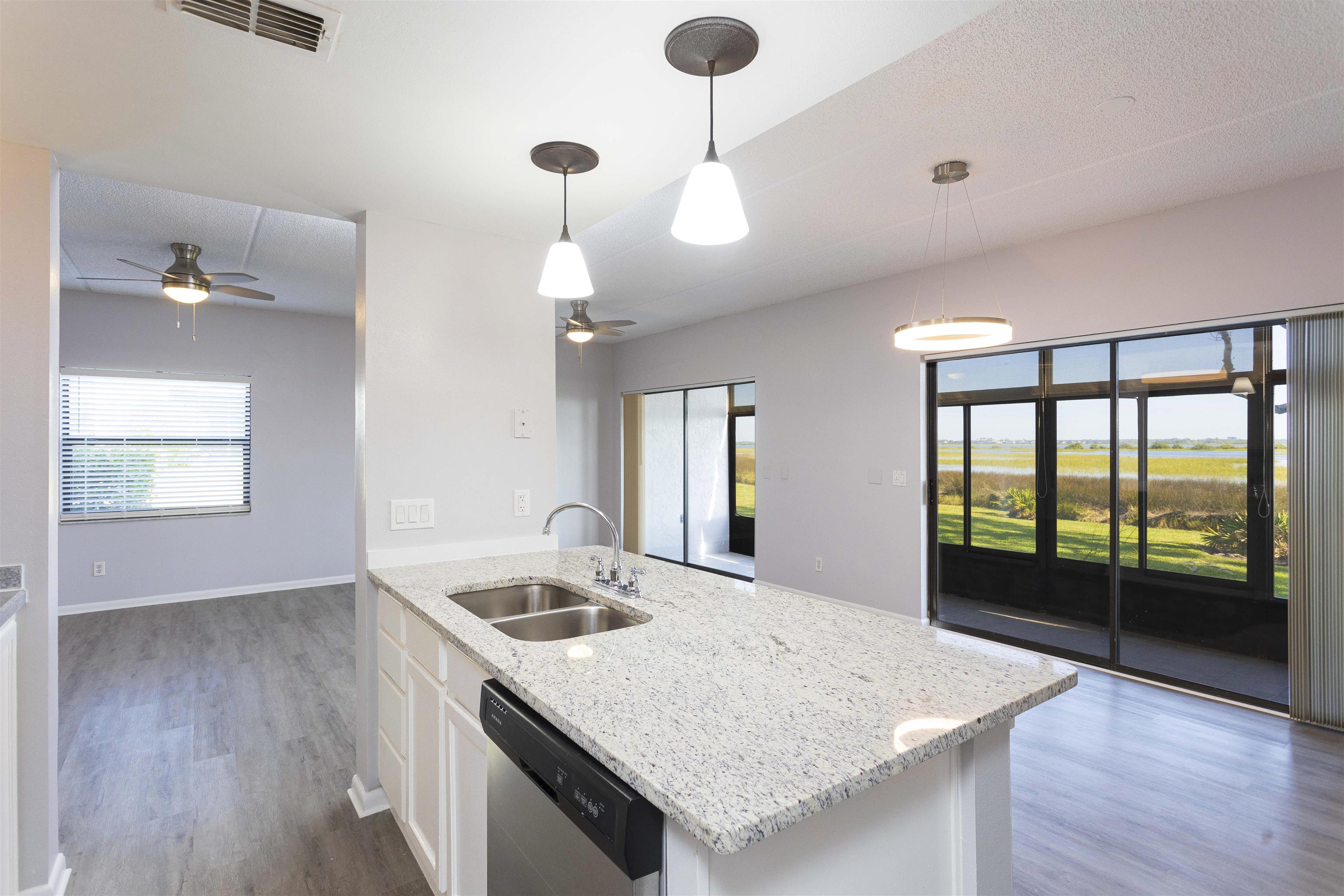 a kitchen with a sink a large window appliances and wooden floor