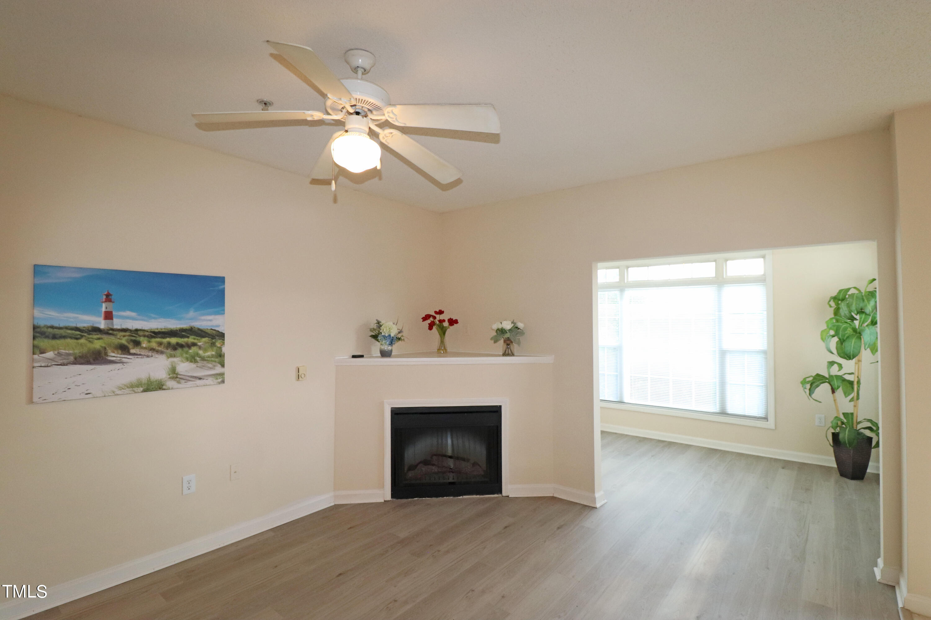 a view of a livingroom with a fireplace a ceiling fan and wooden floor