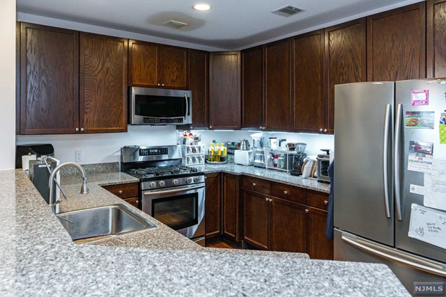 a kitchen with granite countertop wooden cabinets and stainless steel appliances