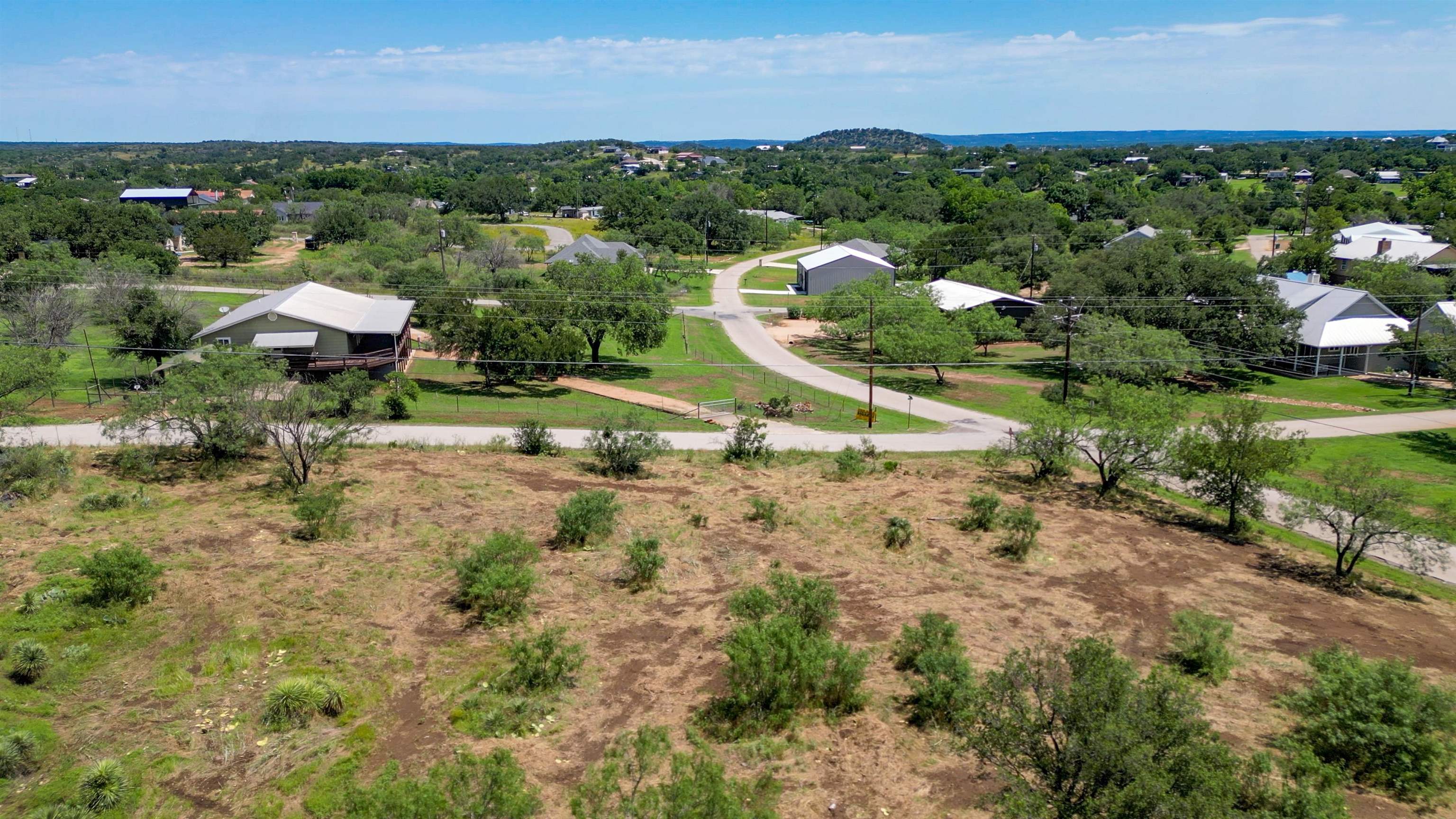 an aerial view of a houses with a yard and lake