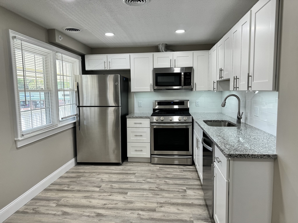 a kitchen with stainless steel appliances granite countertop a refrigerator sink and stove