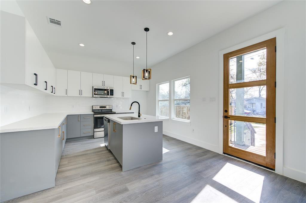 Modern kitchen area with farmhouse sink, quartz kitchen island, and bright cabinets.  Picture is of a previous build by builder and current listing is expected to have similar finishes and layout model.