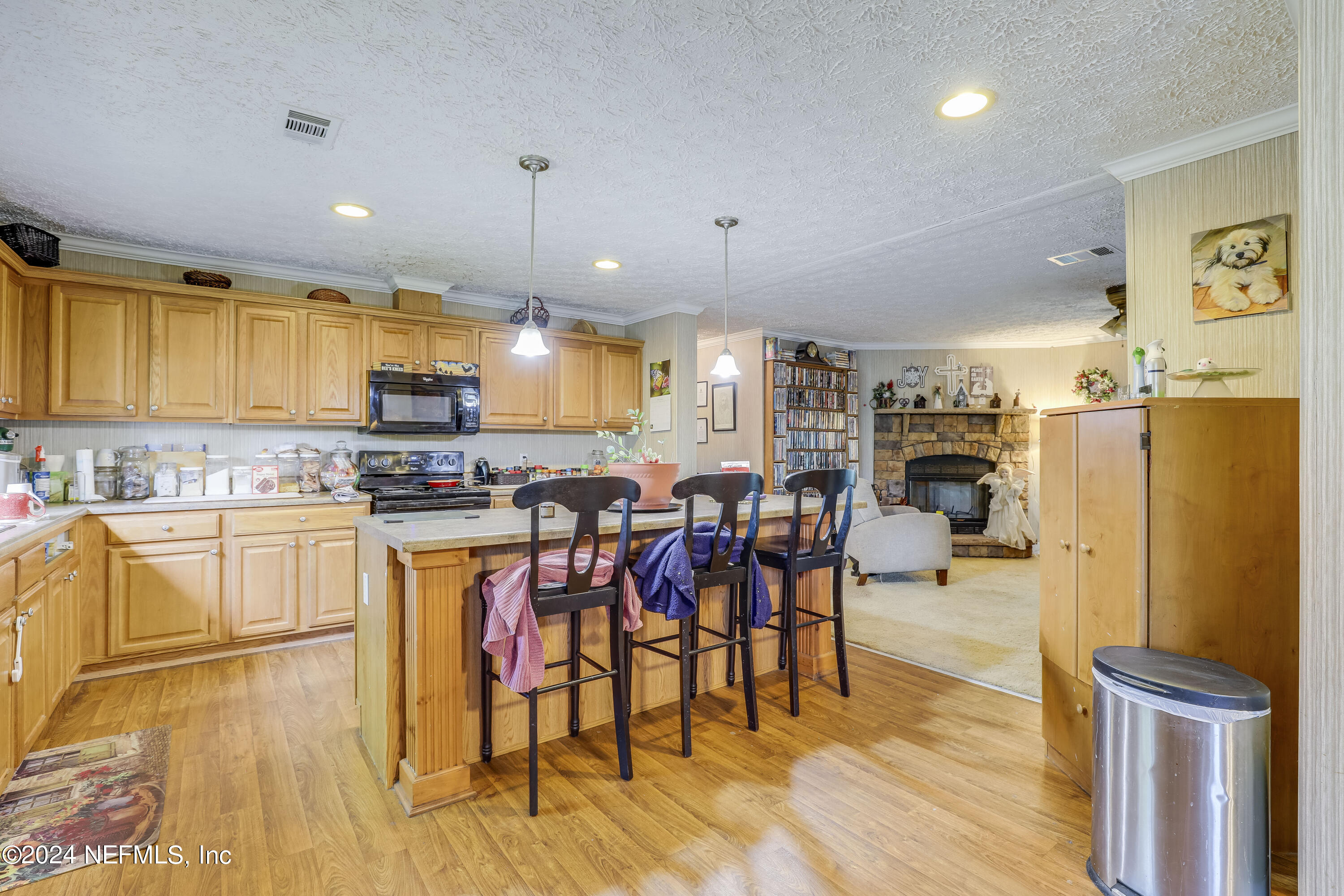 a kitchen with stainless steel appliances kitchen island granite countertop a refrigerator a stove a sink a dining table and chairs with wooden floor