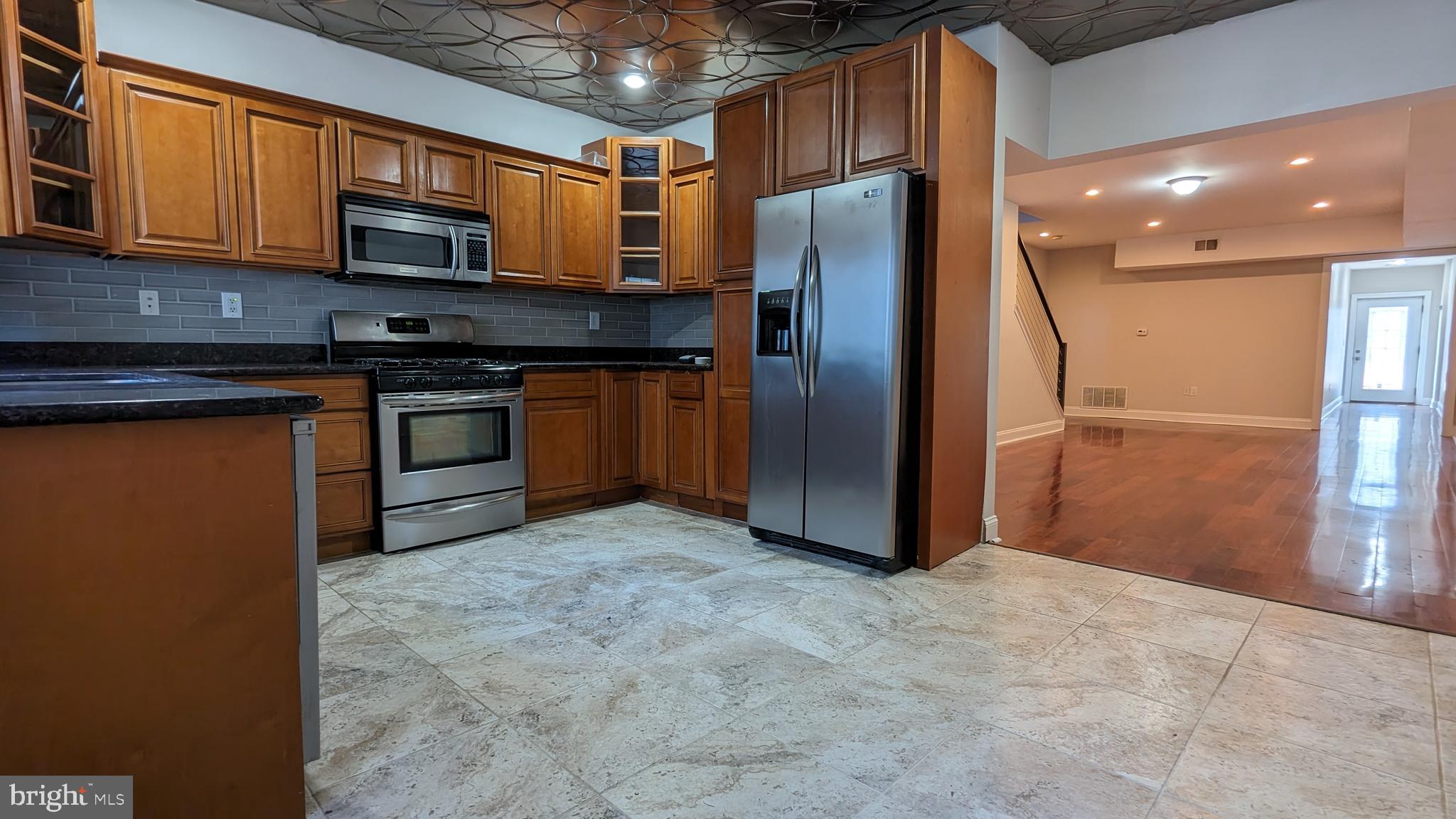 a kitchen with stainless steel appliances granite countertop a refrigerator and a stove