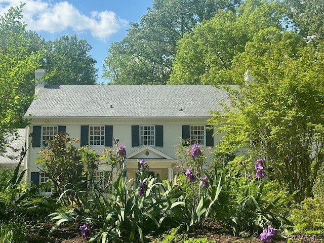 view of a house with potted plants and large trees