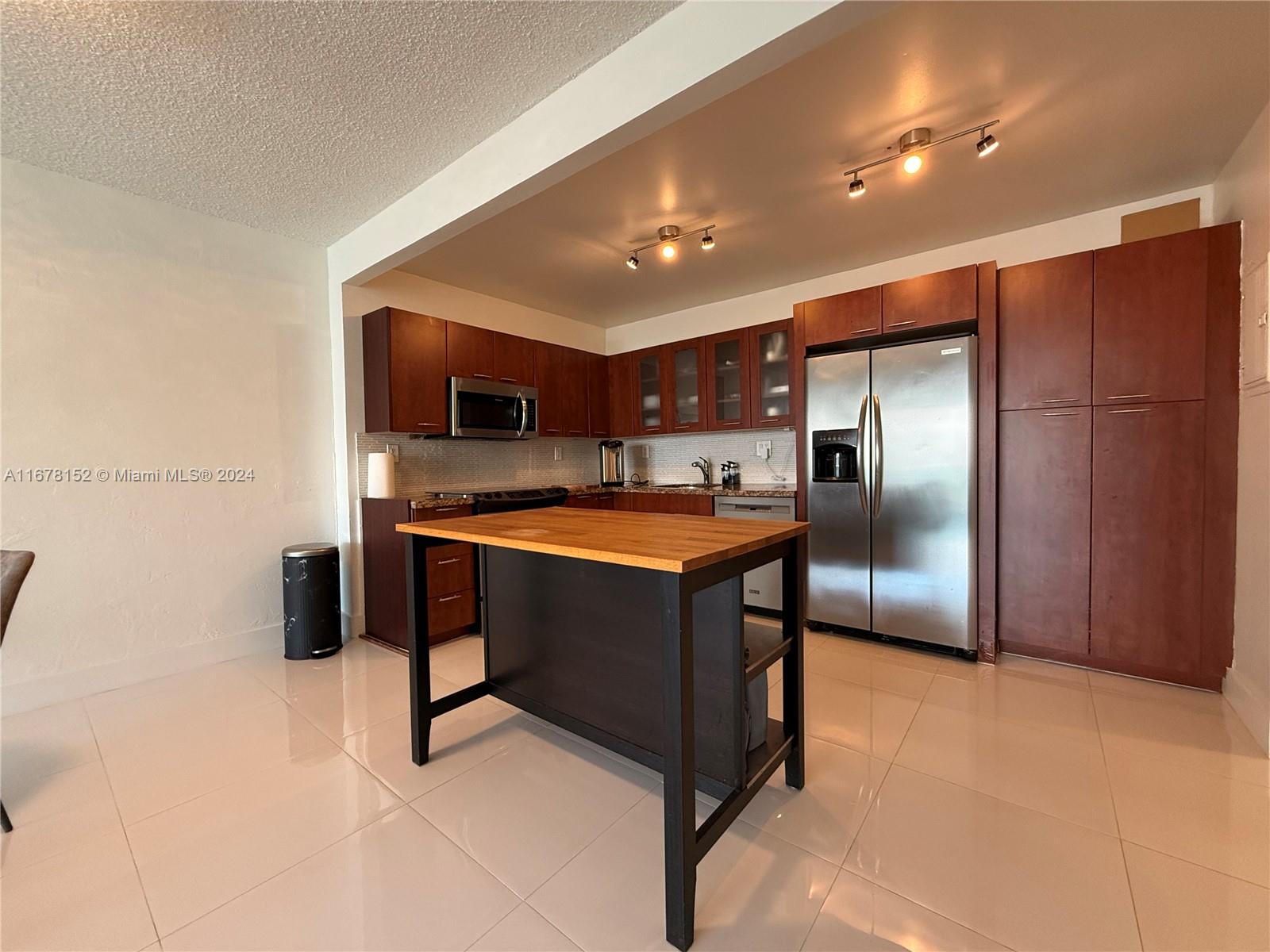 a kitchen with stainless steel appliances kitchen island granite countertop a refrigerator and a stove