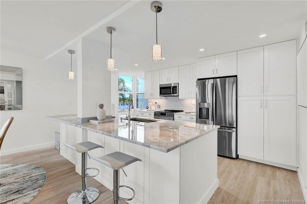 a kitchen with stainless steel appliances granite countertop a kitchen island hardwood floor and a sink