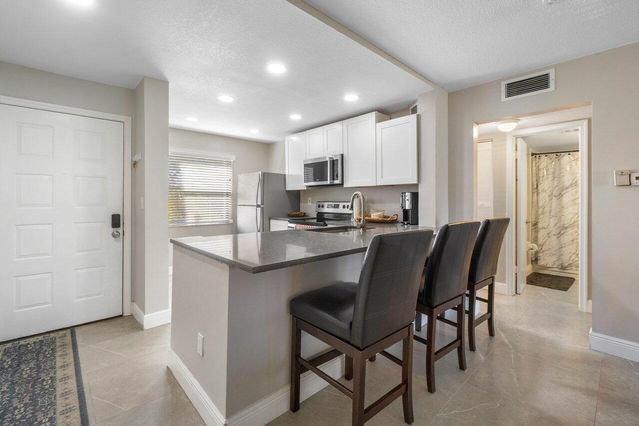 a kitchen with kitchen island a dining table chairs stainless steel appliances and cabinets